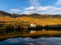 Häuschen im Abendlicht und goldgelb leuchtende Berge